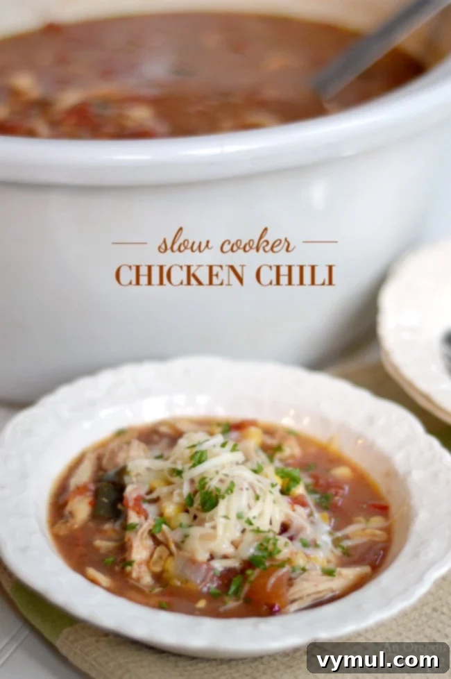 Ultimate Chicken Chili Slow Cooker and Stovetop Recipe 2 Slow Cooker Chicken Chili served in a bowl, garnished with cheese and fresh cilantro, ready to be enjoyed.