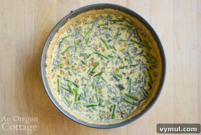 Pouring the egg and half-and-half mixture over the vegetables in the quiche.