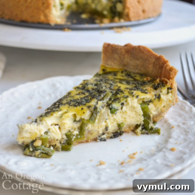 A perfectly cooked piece of healthy asparagus quiche with a flaky press-in-the-pan crust, presented on a plate.