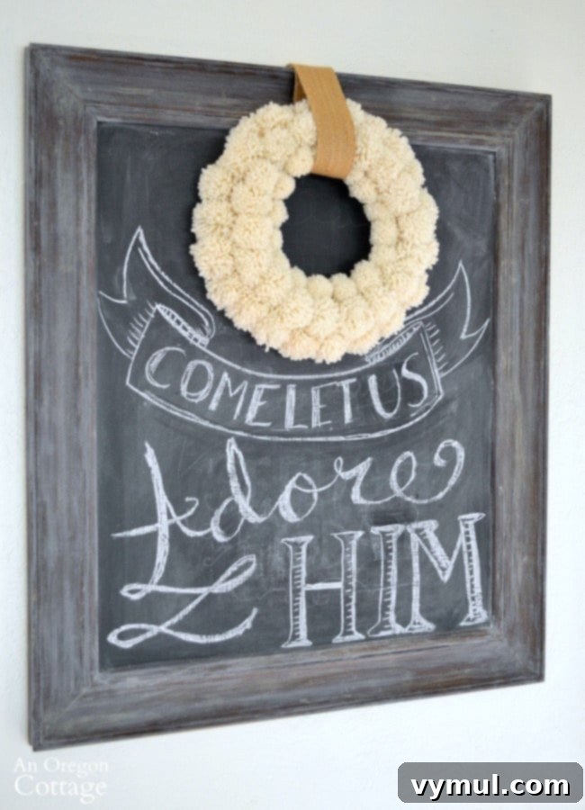 A creamy DIY pom pom wreath highlights a Christmas chalkboard.