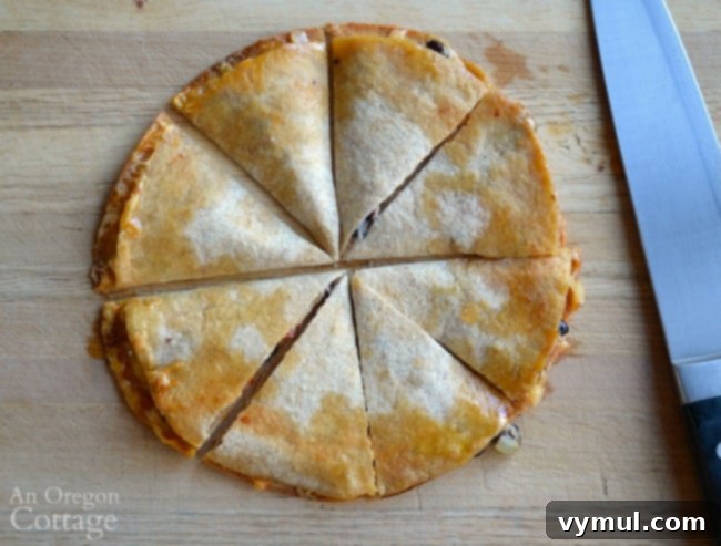 Black Bean Quesadilla Magic 5 Close-up of a baked black bean quesadilla sliced into triangles, showcasing the melted cheese, black beans, and vegetables inside.