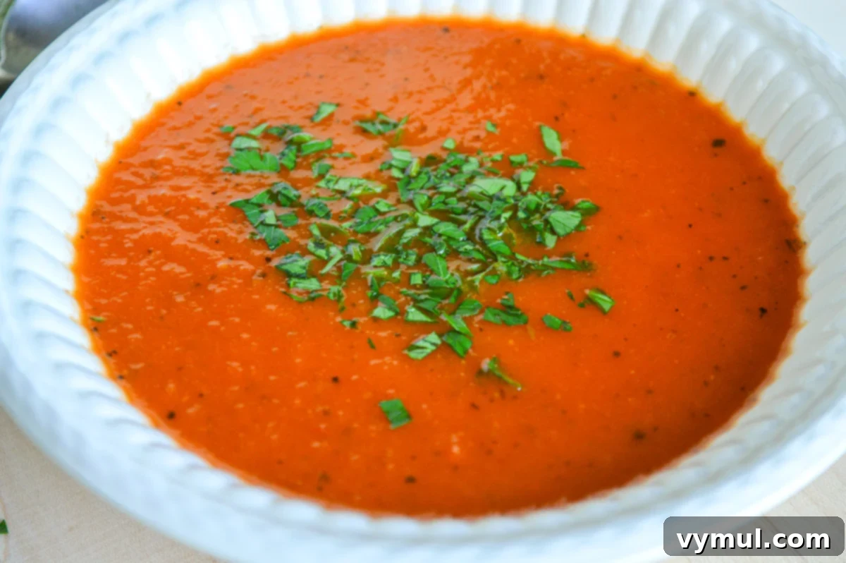 Homemade Tomato Soup Perfection: Say Goodbye To Canned Forever 3 Fresh basil leaves sprinkled over a bowl of vibrant homemade tomato soup.