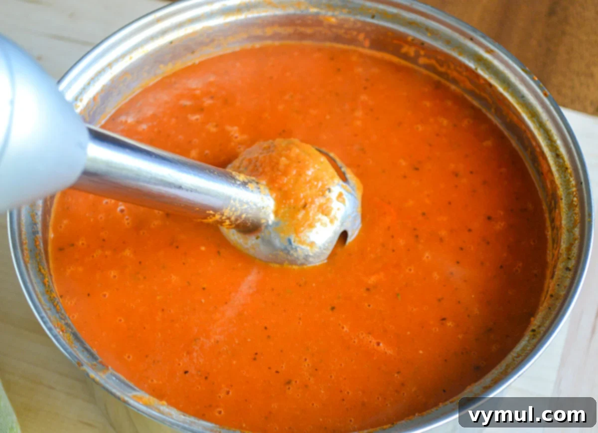 Homemade Tomato Soup Perfection: Say Goodbye To Canned Forever 5 An immersion blender smoothly blending homemade tomato soup directly in the pot.