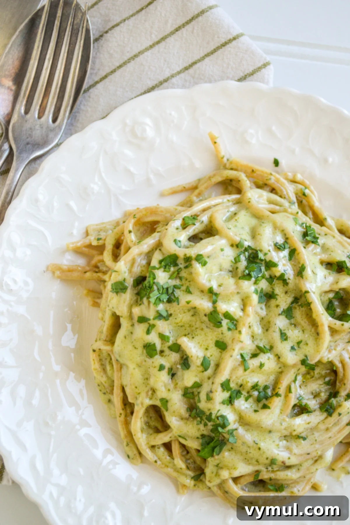 creamy pesto pasta with parsley on white plate 