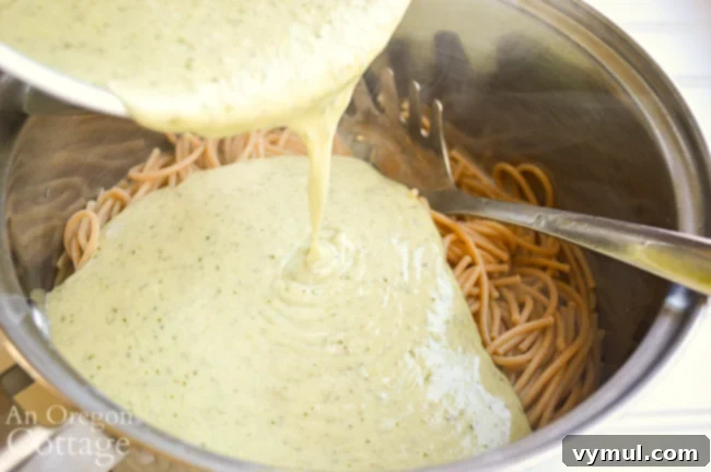 Pouring sauce on pasta for Creamy Pesto Pasta