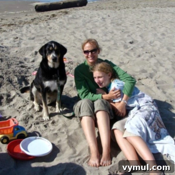 Samson, a large, happy dog, sitting with the family on a beach.