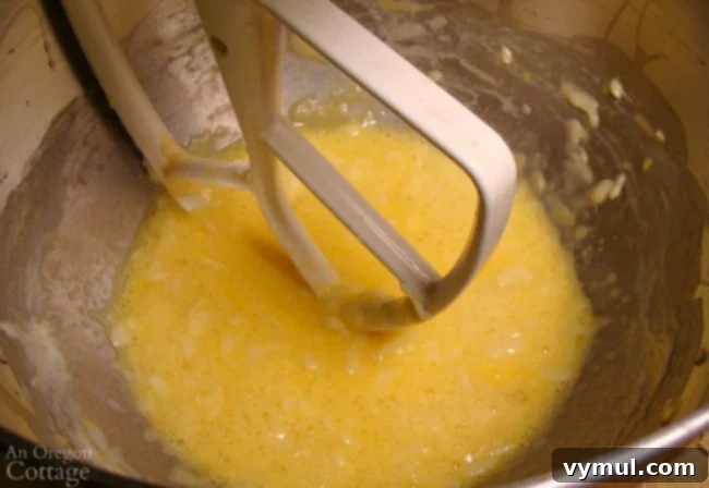 Pillowy Soft 100% Whole Wheat Dinner Rolls 4 Mixed honey, butter, eggs, milk, and yeast mixture in a stand mixer bowl, showing slight lumps of butter.