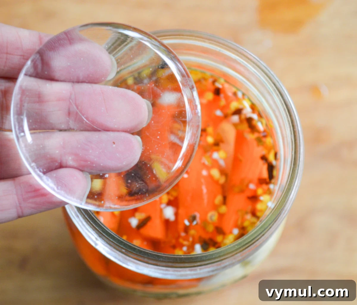 adding glass lid to top of jar with vegetables