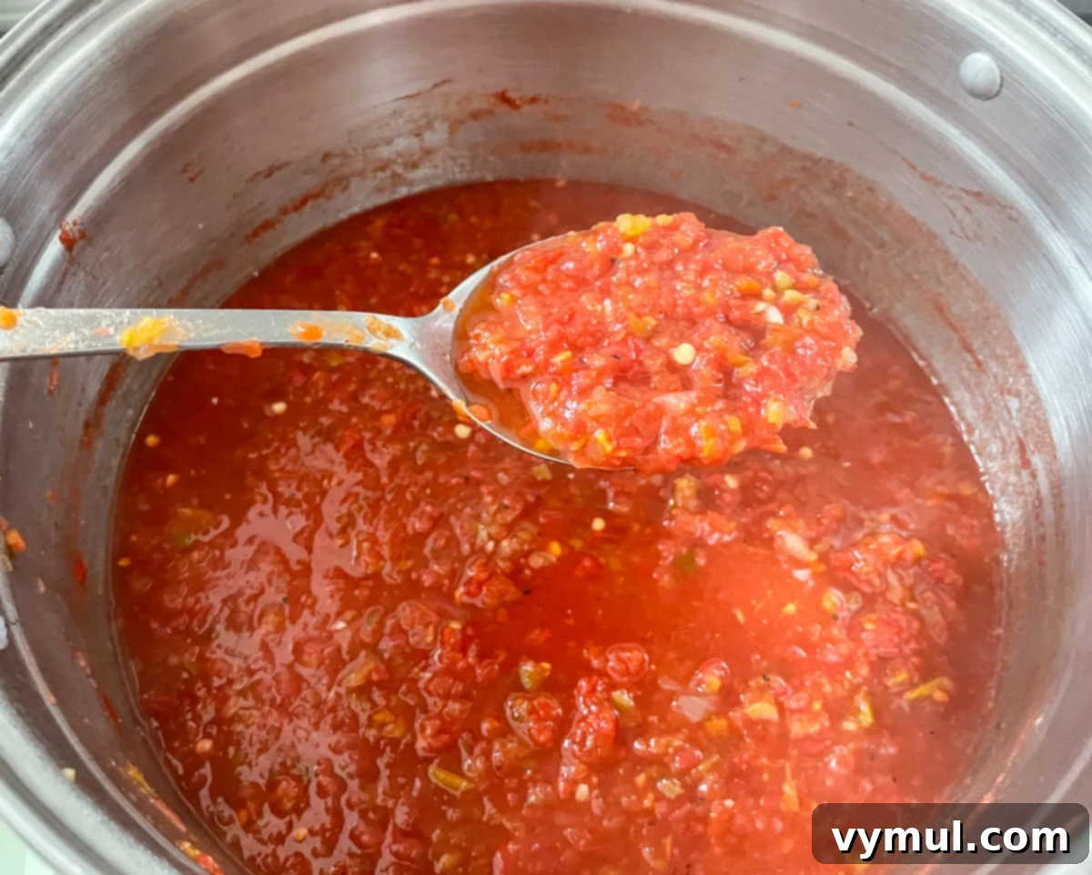 Thick, cooked homemade salsa, glistening in a stockpot, ready to be ladled into canning jars for preservation.