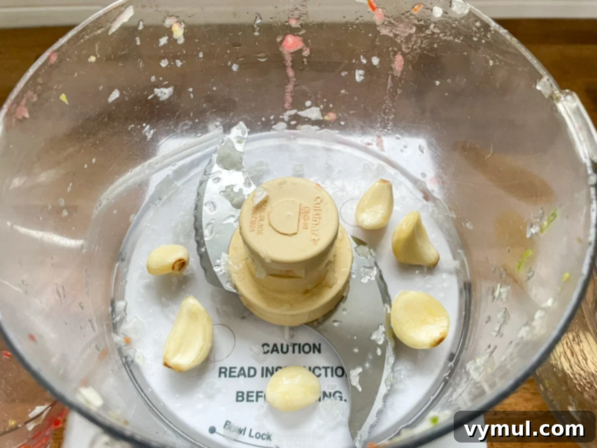 Garlic cloves in a food processor, demonstrating the quick method for mincing garlic for salsa.