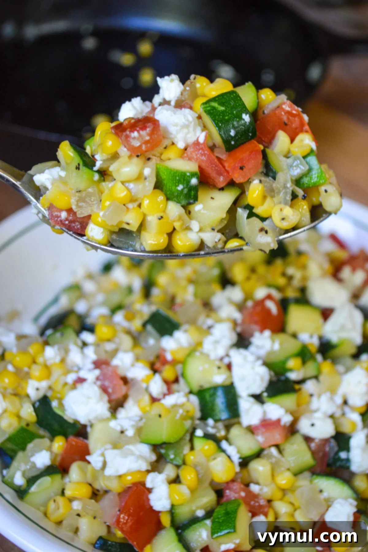 Sunny Zucchini, Corn, and Tomato Skillet with Feta 2 spoon full of zucchini corn and tomato saute with feta cheese, showcasing vibrant summer vegetables