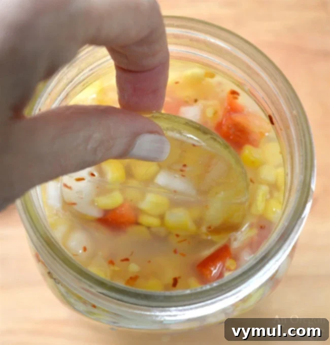 Easy 5-Minute Fermented Corn Relish Magic 8 Adding a glass weight to Easy Fermented Corn Relish in a jar
