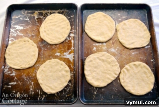 Individual pizza dough rounds shaped on baking sheets with cornmeal