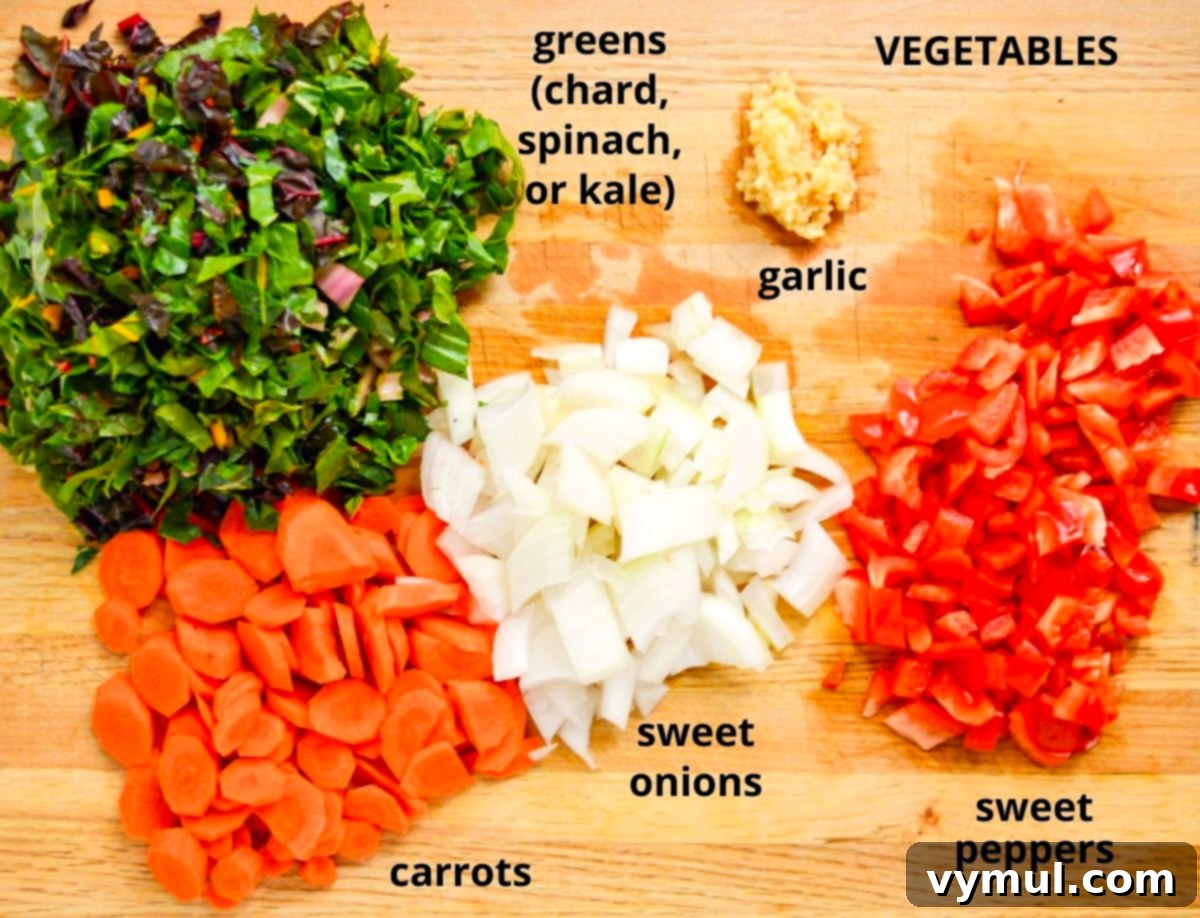 Freshly chopped onions, garlic, and carrots on a wooden cutting board, prepped for the shrimp orzo skillet meal.