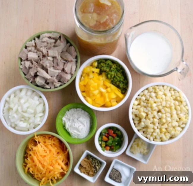 A flat lay of fresh and pantry ingredients for Mexican chicken corn soup: chopped onion, jalapeños, bell peppers, corn, cooked chicken, garlic, spices, broth, and milk.