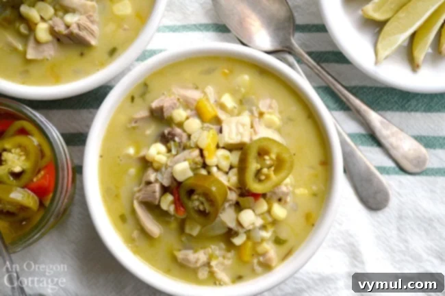 A close-up of a bowl of creamy Mexican chicken corn soup, topped with pickled jalapeños and a fresh lime wedge, ready to be enjoyed.