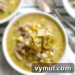 A hearty bowl of creamy Mexican chicken corn soup, garnished with fresh cilantro and a lime wedge, ready to be served.