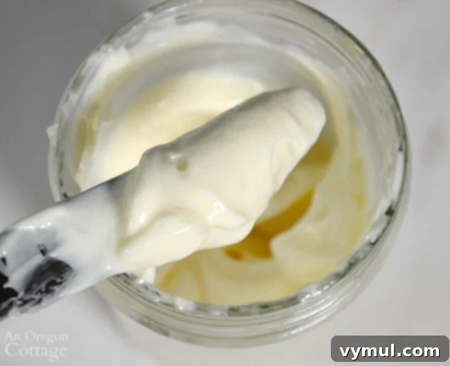 Close-up of homemade mayonnaise on a knife blade, showcasing its thick, creamy texture