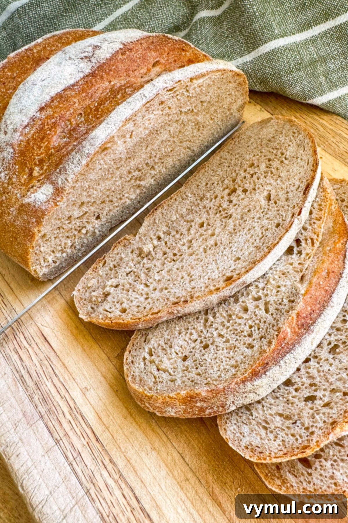 Foolproof Dutch Oven Whole Wheat Artisan Bread 17 Slicing a warm loaf of artisan bread with a serrated knife.