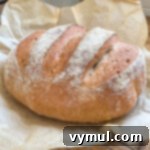 Foolproof Dutch Oven Whole Wheat Artisan Bread 18 Freshly baked loaf of artisan bread on parchment paper.