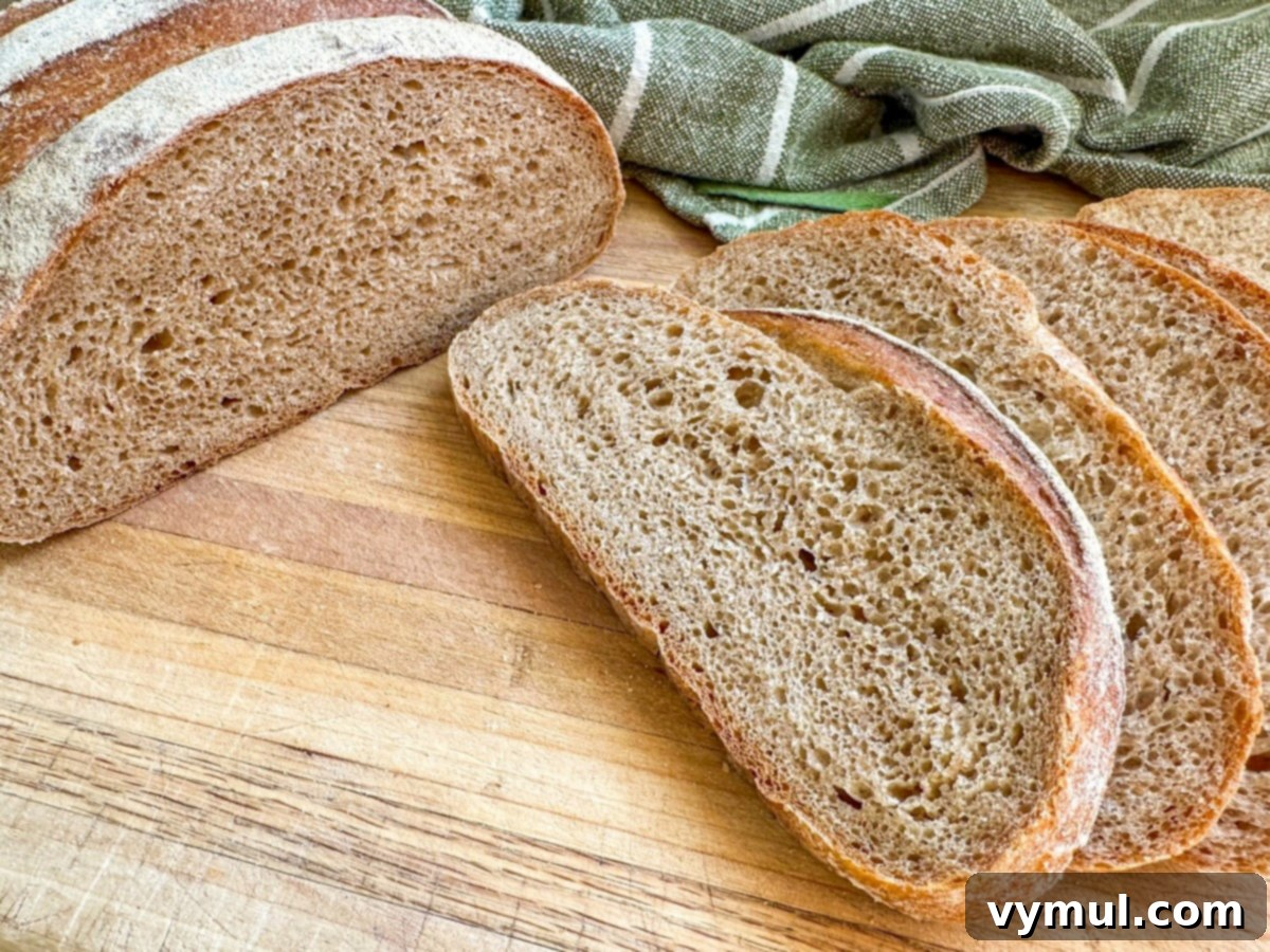 Foolproof Dutch Oven Whole Wheat Artisan Bread 3 Sliced artisan bread loaf on a wooden cutting board, revealing a tender crumb.