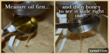 Oil and honey being carefully added to the partially mixed bread dough in a stand mixer bowl.