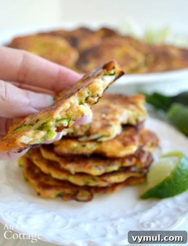 Zesty Zucchini Feta Fritters 9 Close-up of a cut zucchini feta fritter, revealing its savory interior with visible zucchini shreds, feta crumbles, and fresh herbs, ready to be enjoyed.