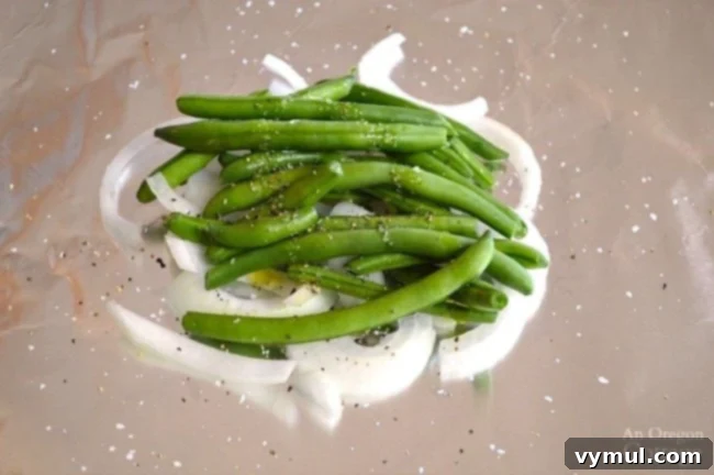 Zesty Lemon Fish and Veggie Grill or Bake Packets 3 Lemon Vegetable Fish Foil Packets layering onions and green beans on a piece of foil