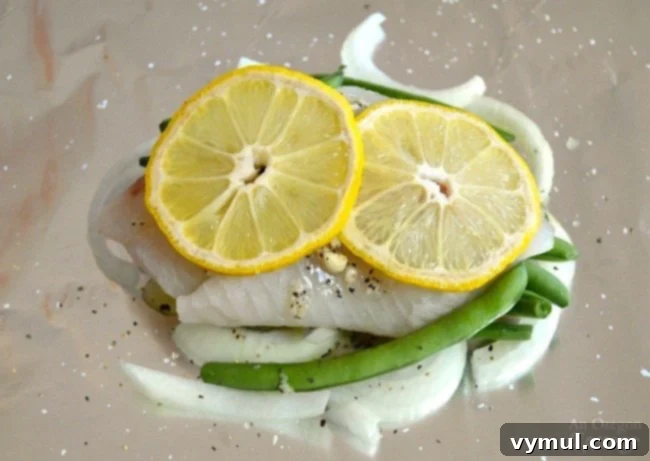 Zesty Lemon Fish and Veggie Grill or Bake Packets 5 Lemon Vegetable Fish Foil Packets with lemon slices on top of fish