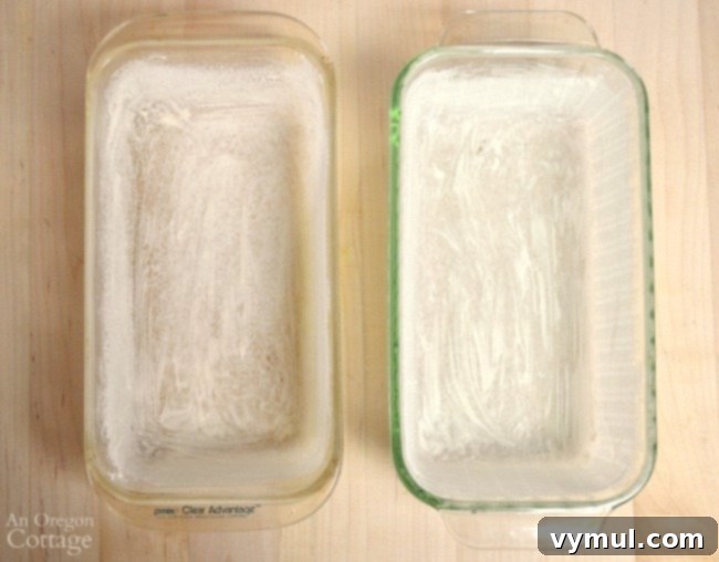 Two loaf pans filled with orange zucchini bread batter, ready for baking