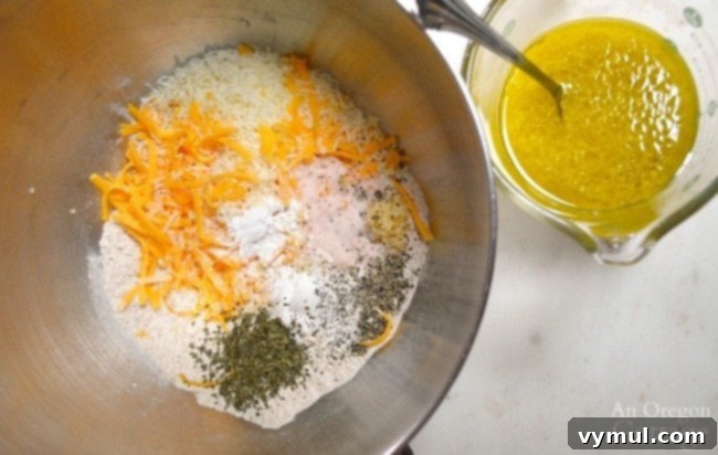 All the ingredients for Savory Zucchini Bread with Cheese laid out on a table, including flour, eggs, oil, cheese, herbs, and grated zucchini.