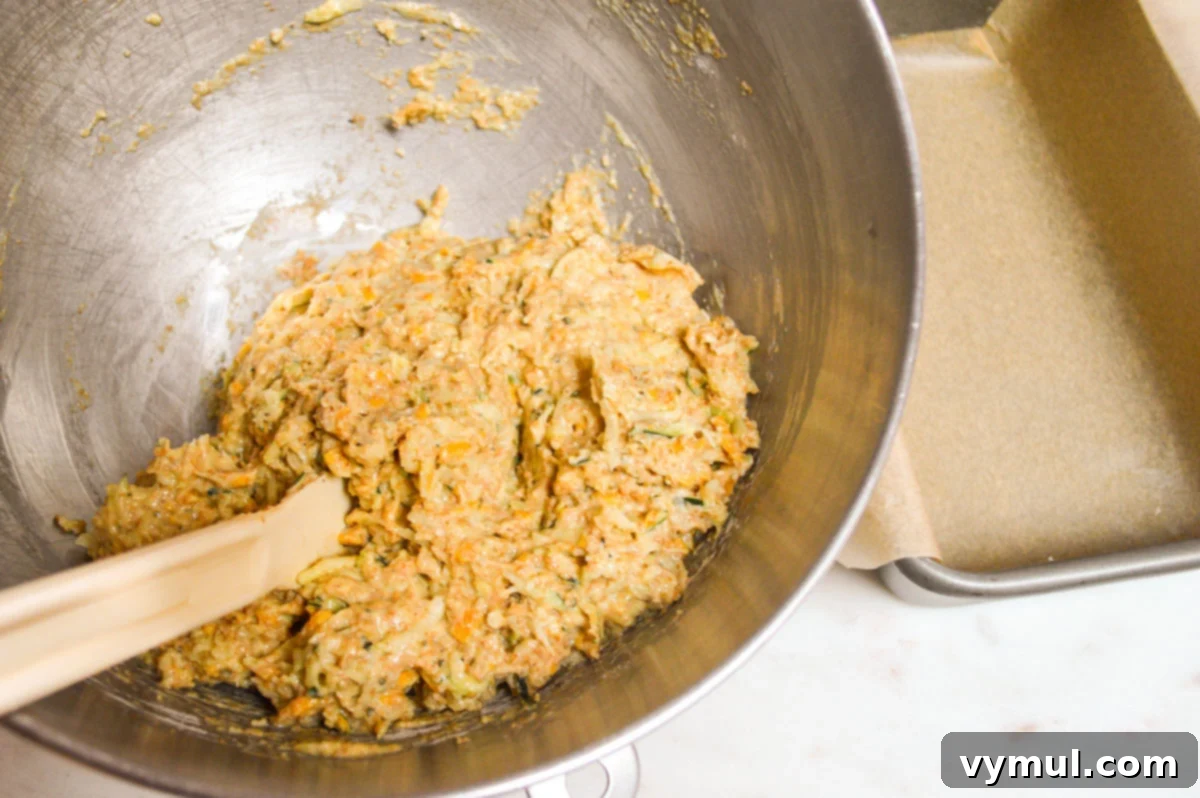 Thick zucchini bread batter mixed with cheese and herbs, ready to be spread into a loaf pan.