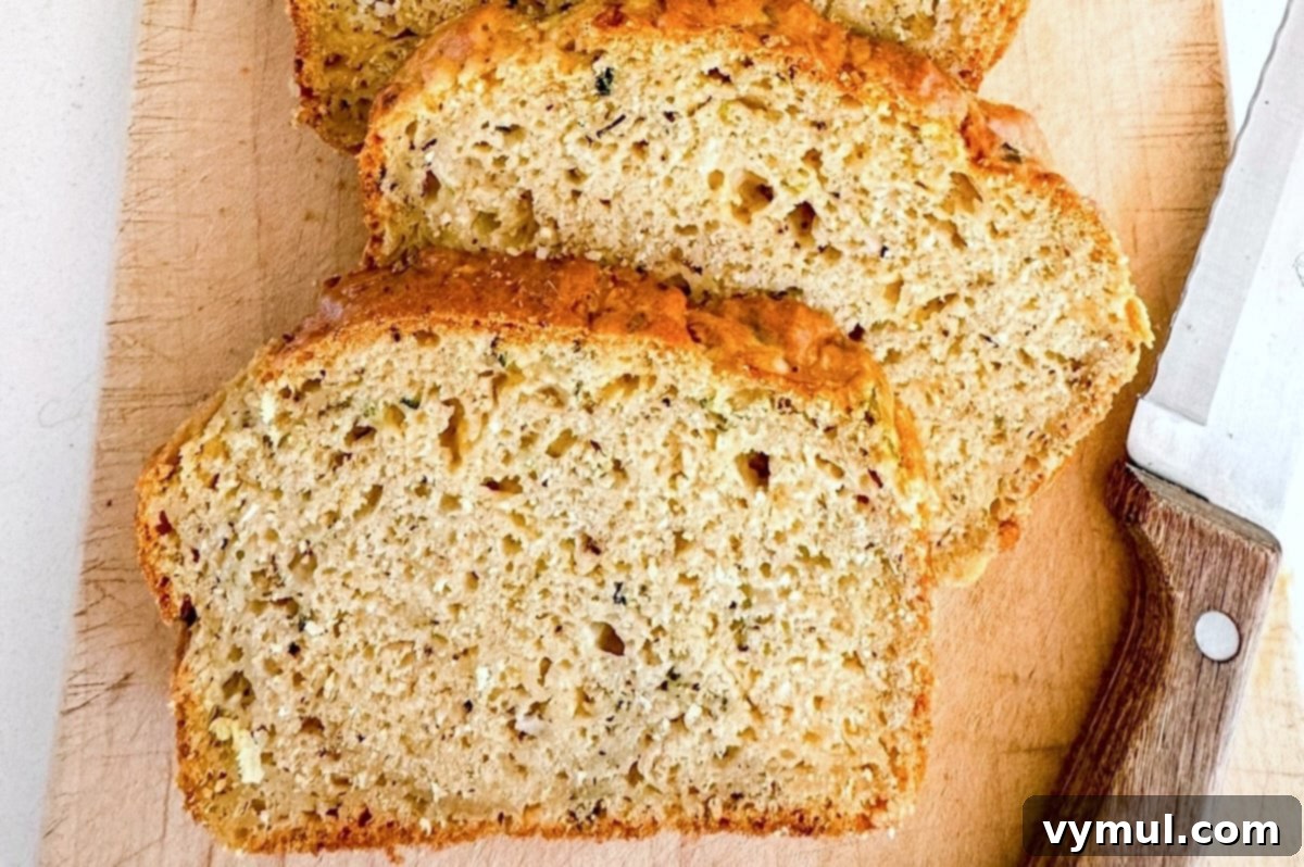 Slices of savory zucchini bread baked in an 8.5x4.5-inch pan, displaying a taller, more substantial loaf.
