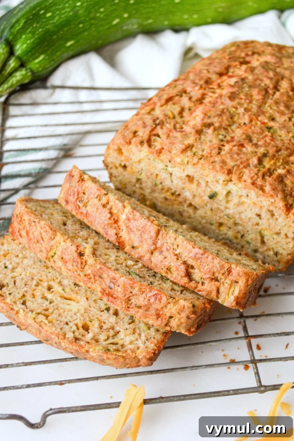 Freshly baked slices of savory zucchini bread with cheese, cooling on a wire rack, showcasing its moist texture and golden-brown crust.