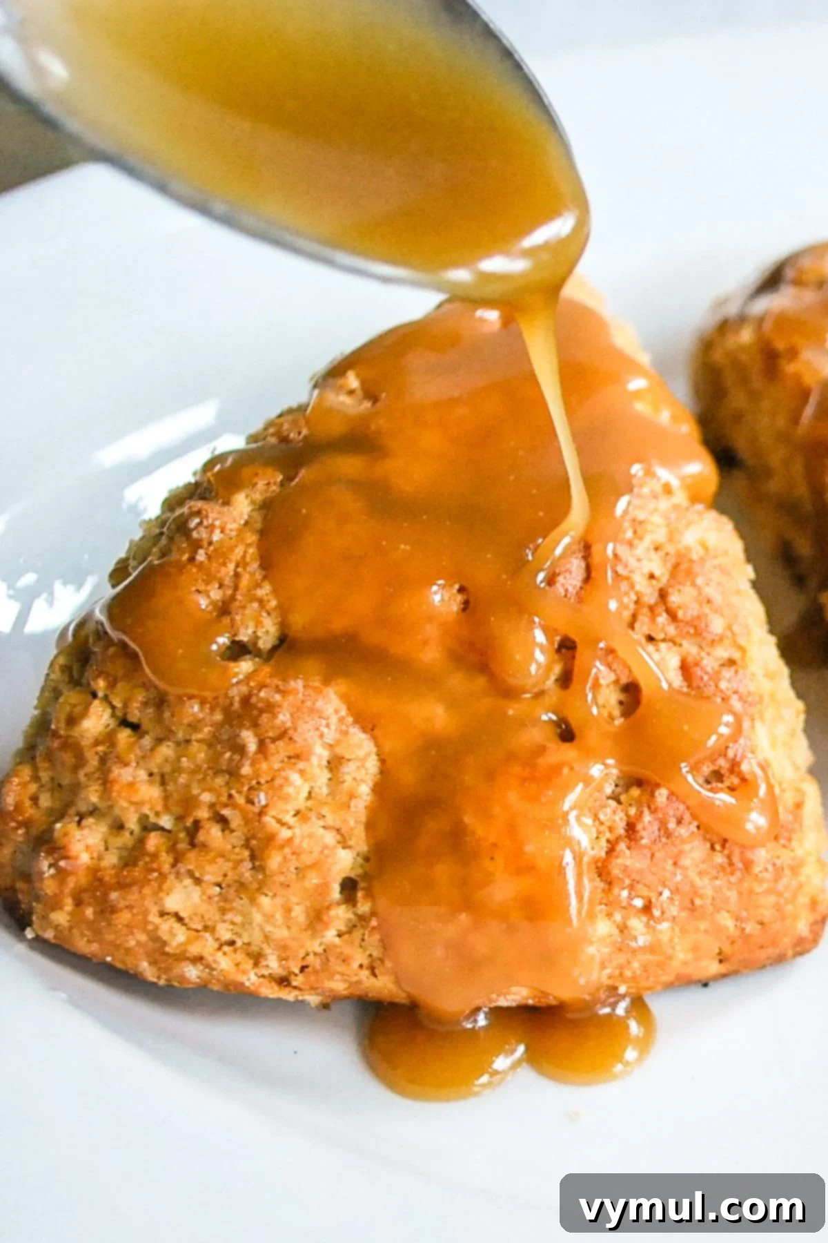 Luscious Double Apple Scones with Golden Caramel Glaze 2 Caramel sauce being drizzled generously over a warm, tender apple scone, highlighting its moist texture and golden-brown crust.