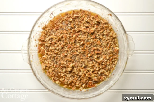 Close-up of the buttery caramel layer with chopped pecans in a baking pan, ready for the coffee cake batter.
