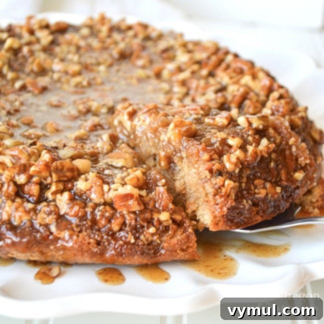 A whole sticky bun sourdough coffee cake on a white serving plate, topped with golden caramel and crunchy pecans.