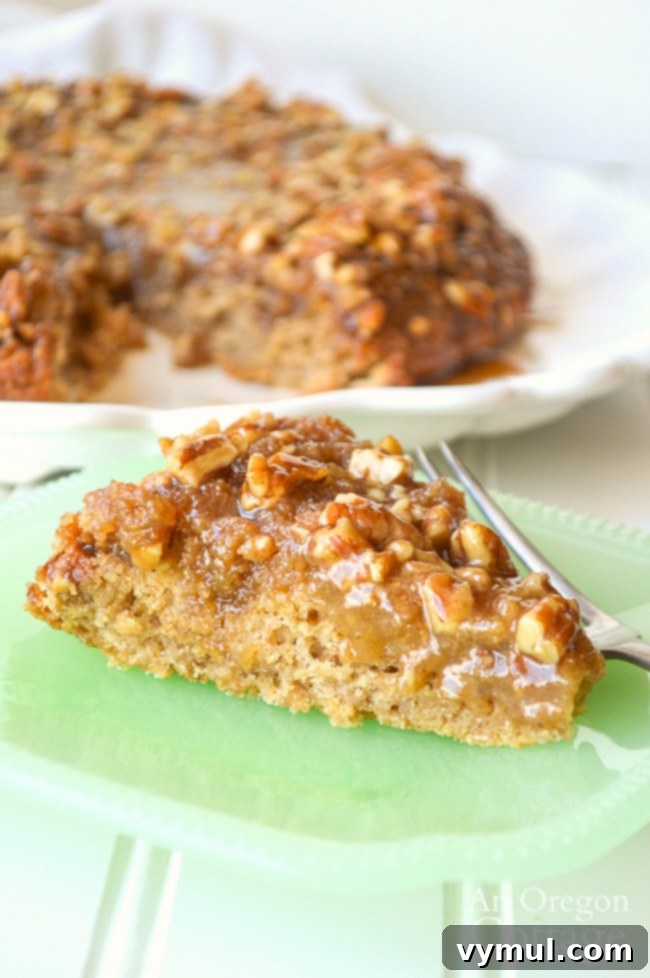 A close-up of a single slice of sticky bun sourdough coffee cake, showcasing the moist cake and gooey caramel pecan topping.