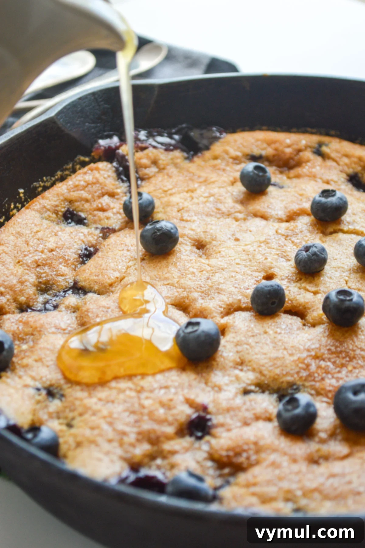 pouring sauce onto baked blueberry cobbler