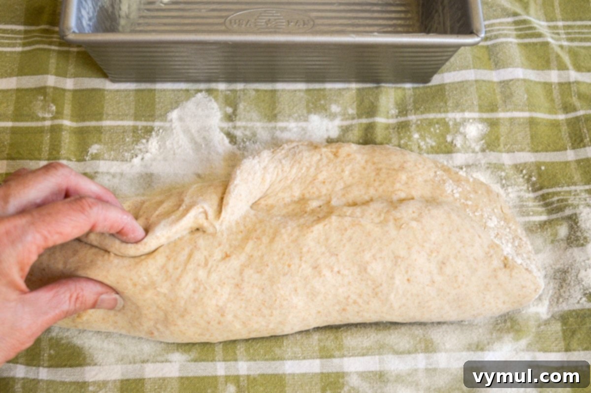 shaping bread dough into a loaf on a tea towel
