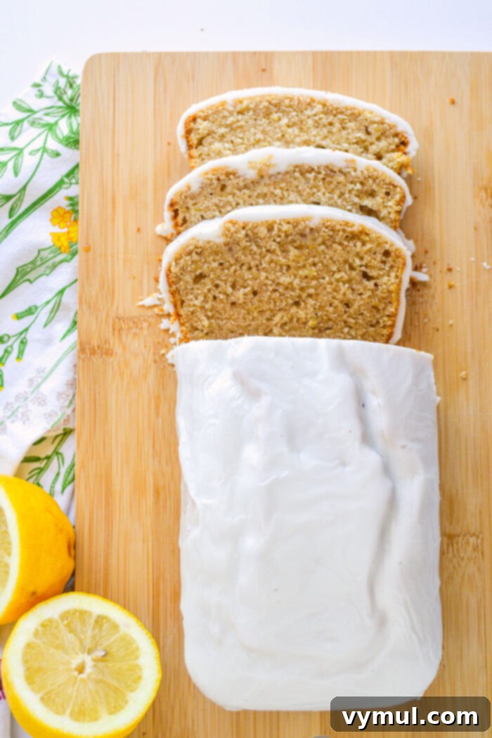 Bright Lemon Sourdough Loaf from Discard 2 Sliced glazed sourdough lemon bread on a cutting board, showcasing its moist texture and shiny glaze.
