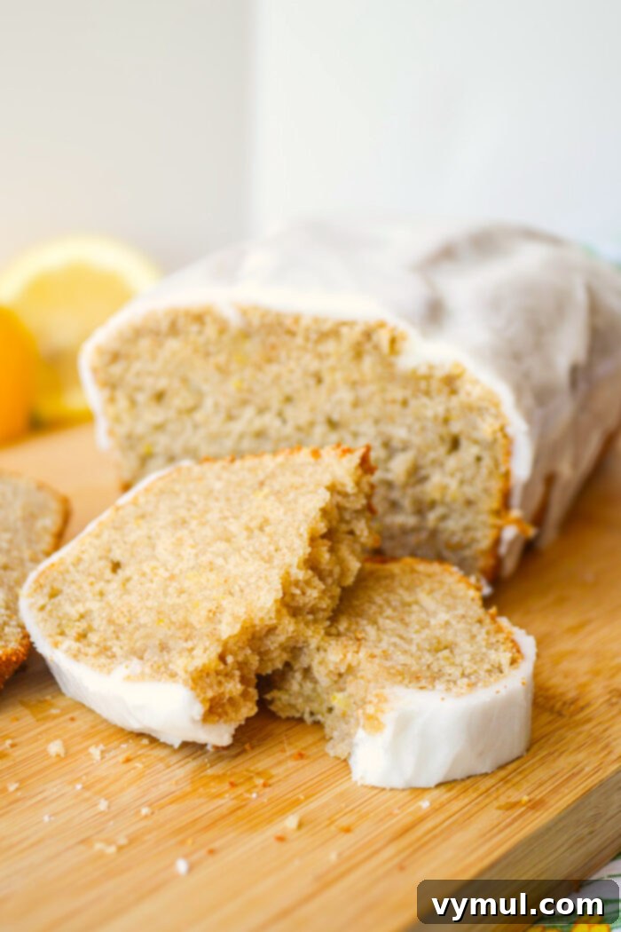 Bright Lemon Sourdough Loaf from Discard 3 Close-up of a slice of sourdough lemon bread with a piece broken off, revealing its moist interior.