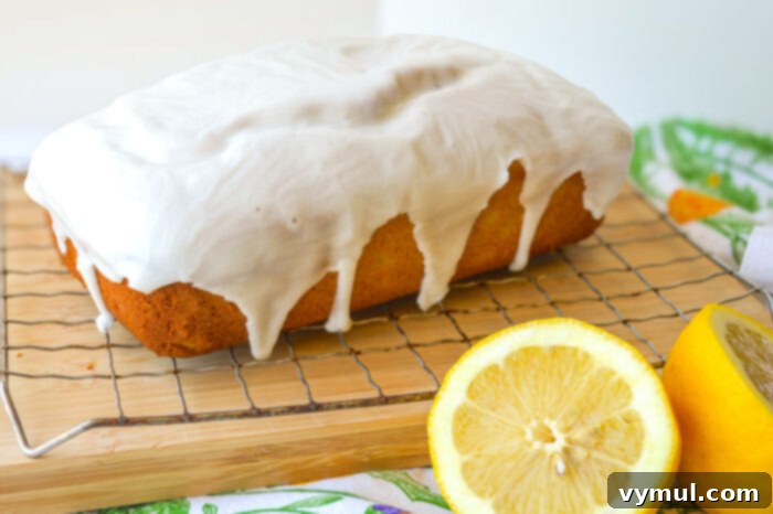 Bright Lemon Sourdough Loaf from Discard 7 Warm lemon bread loaf cooling on a wire rack with a drizzle of glaze.