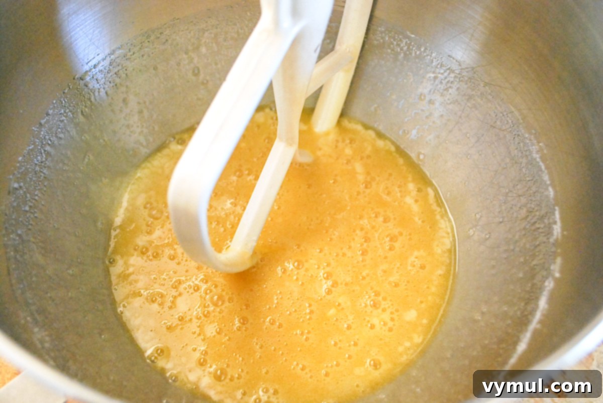 Wet ingredients for zucchini lemon bread, including eggs, sugar, oil, and lemon juice, being mixed in a large bowl.