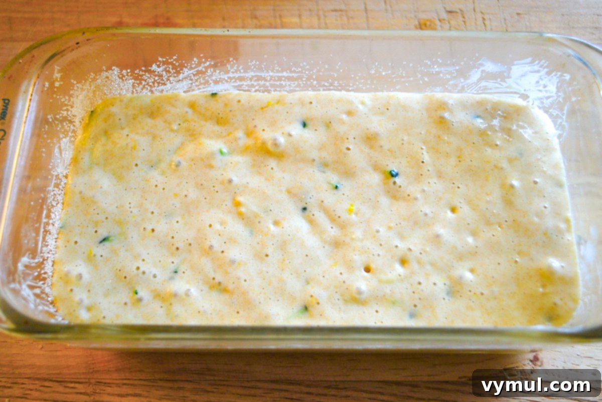 Zucchini lemon bread batter poured into a prepared loaf pan, ready for baking.