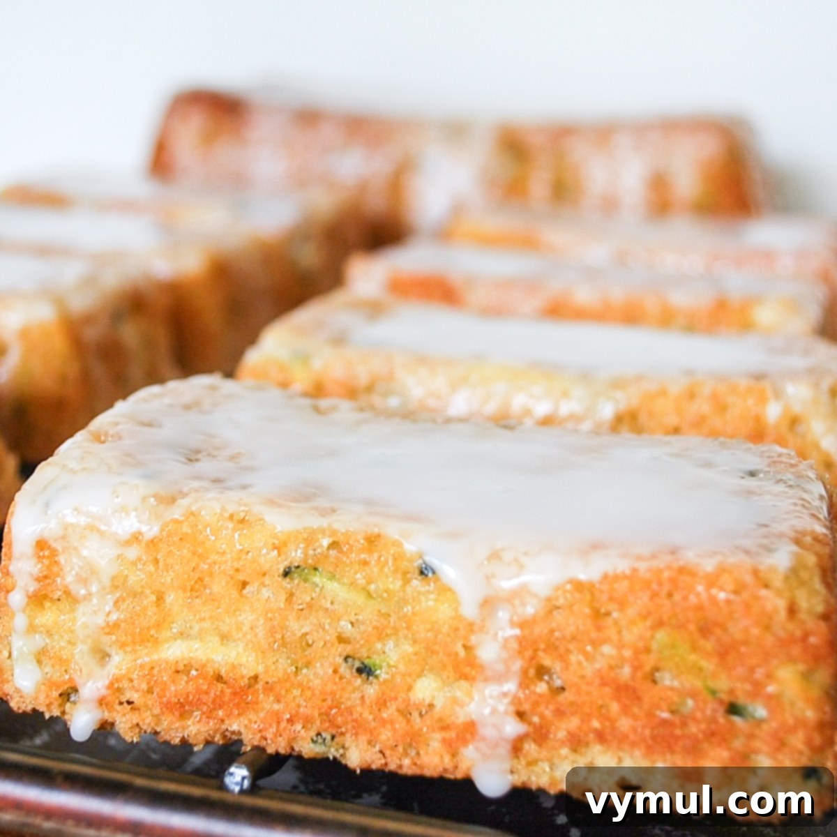 A perfectly glazed lemon zucchini bread loaf, showcasing its beautiful texture and golden-brown crust, ready to be sliced and served.