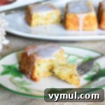 A slice of zucchini lemon bread on a plate with a fork, showing its moist crumb and lemon glaze.
