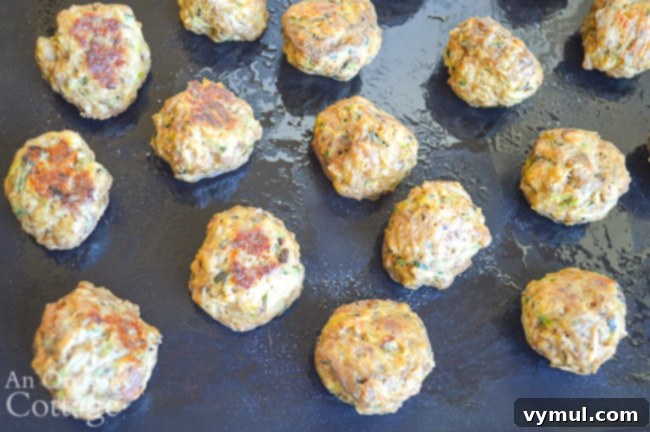 A vibrant close-up of baked zucchini meatballs, garnished with fresh herbs, showcasing their inviting texture.