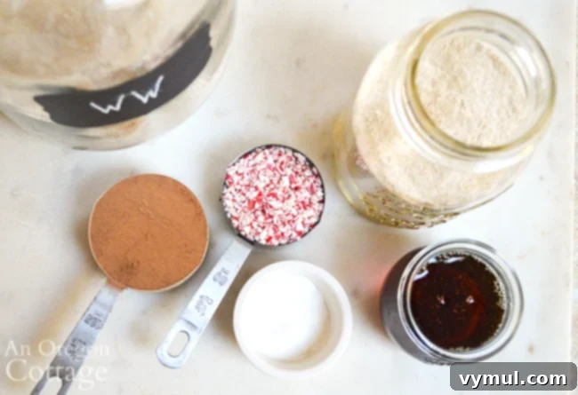 Key dry ingredients for healthy chocolate mint cookies in a jar, including whole wheat flour, cocoa, and crushed peppermint.