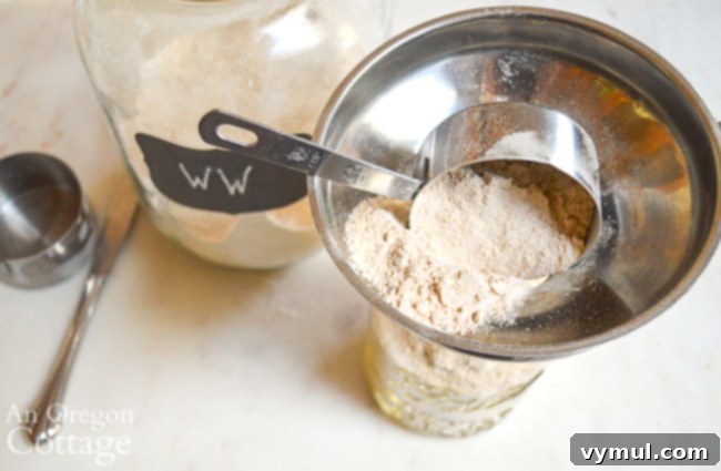 Layering dry ingredients like flour, cocoa powder, and crushed peppermint into a quart-sized mason jar to create a healthy chocolate mint cookie mix gift.